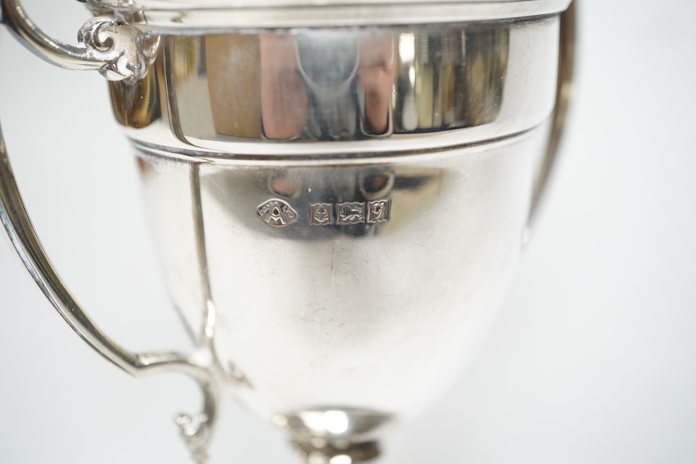 A pair of Edwardian silver dwarf candlesticks, of tapering design, C.S Green & Co, Birmingham, 1908, 13.2cm, together with four small silver trophy cups, a silver napkin ring and a plated trophy cup. Condition - poor to